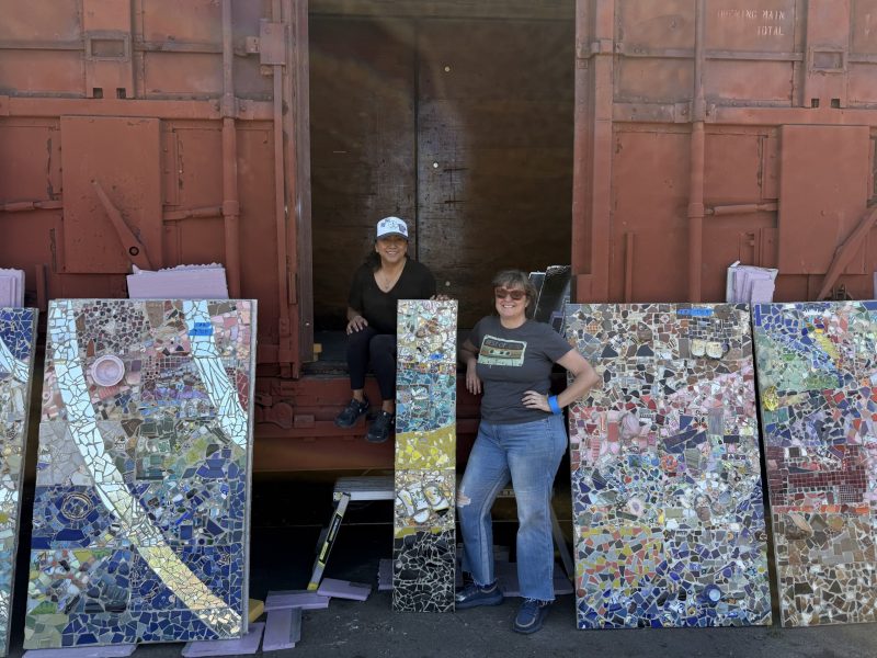 Kristina Young and her "right hand woman" Sandra Cruz-Wilson stand next to the box car that became the new home to the Quake Mosaic, created under Young's direction. Izzi Valencia photo