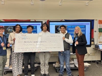 students hold giant check in classroom