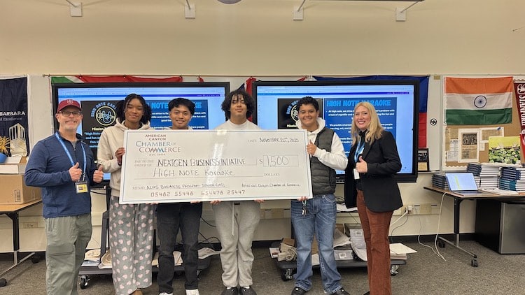 students hold giant check in classroom