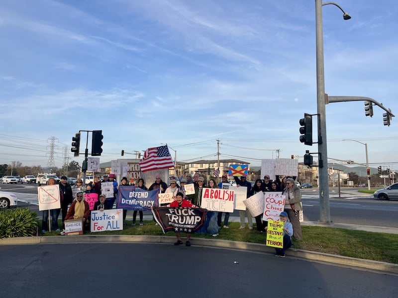Group of people sit and pose for a photo holding protest signs