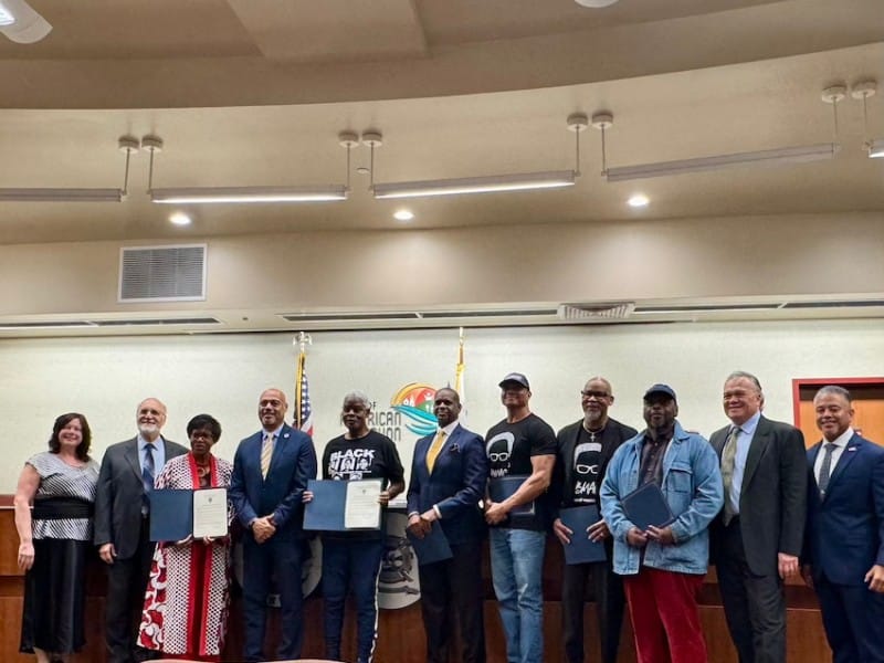 A group of people stands for a photo in city council chambers