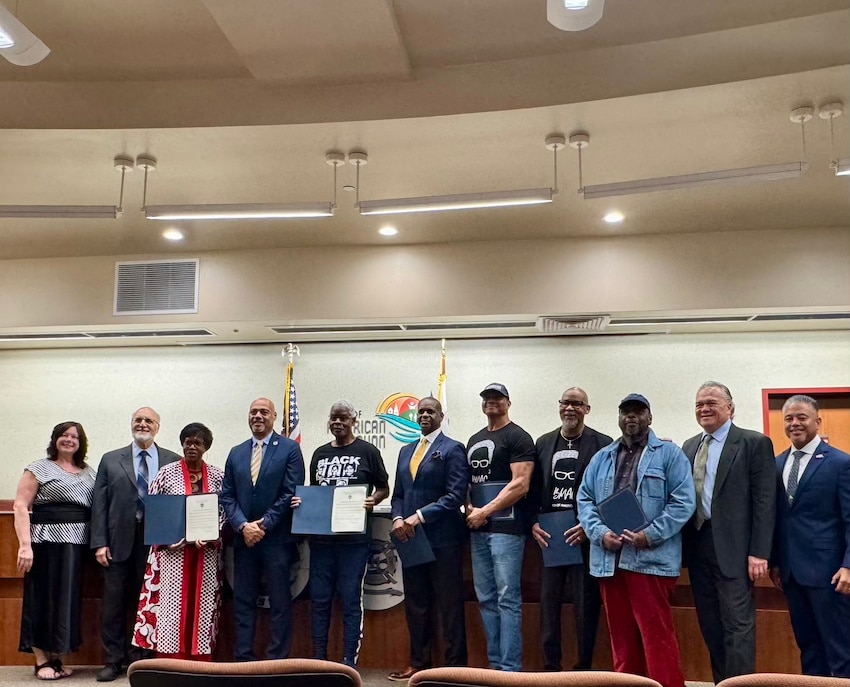 A group of people stands for a photo in city council chambers