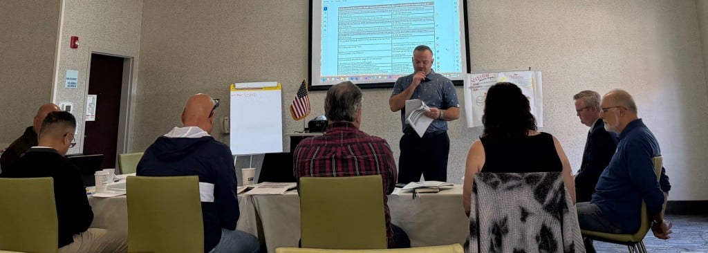 people standing or in chairs in a conference room