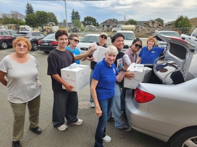teenagers and adults putting boxes in car