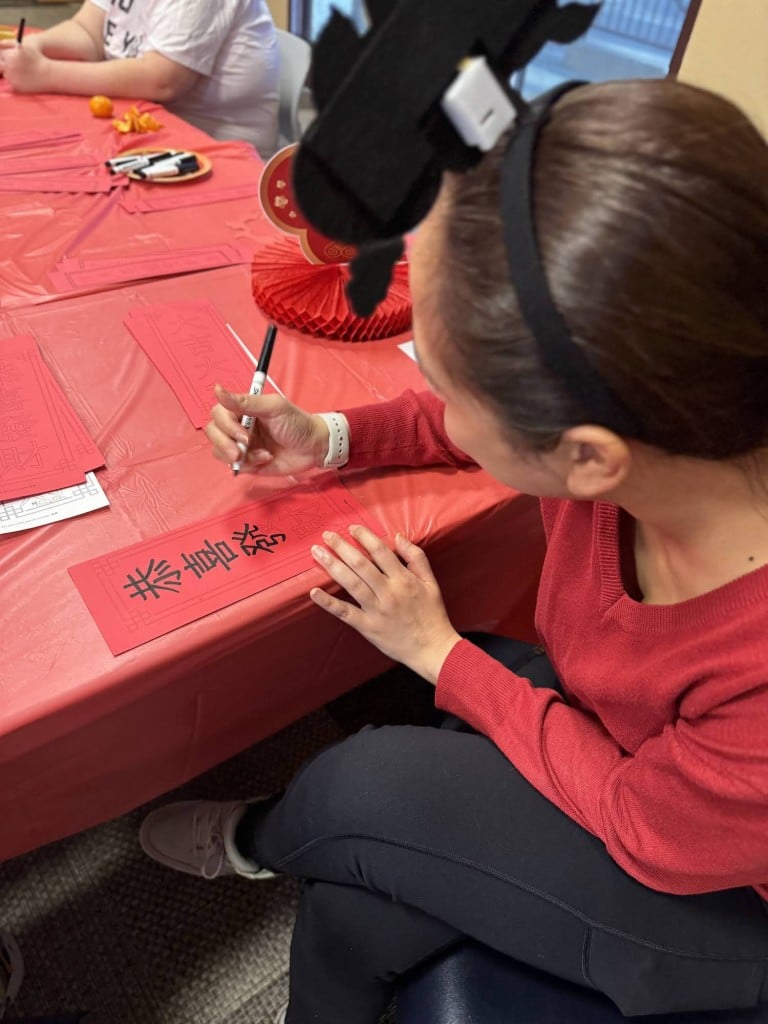 woman with calligraphy pen writing in ink on a red paper