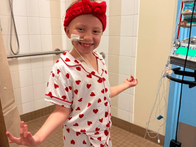child stands smiling in pajamas with hearts on them