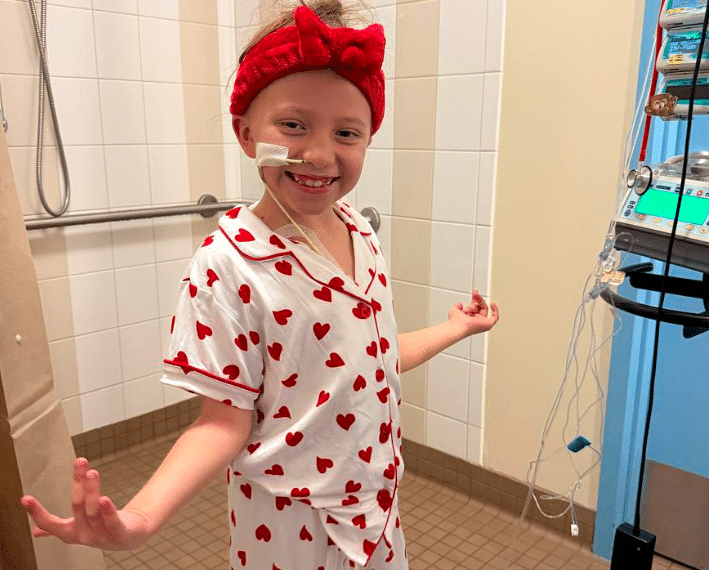 child stands smiling in pajamas with hearts on them