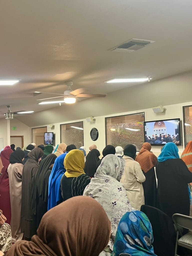 group of muslim women stand in prayer in mosque