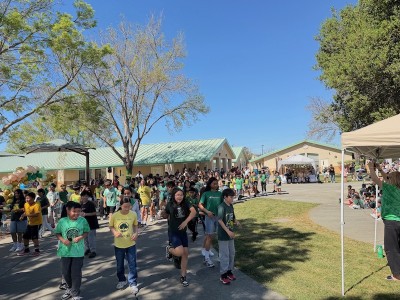 a group of kids walking on a sidewalk outside a school