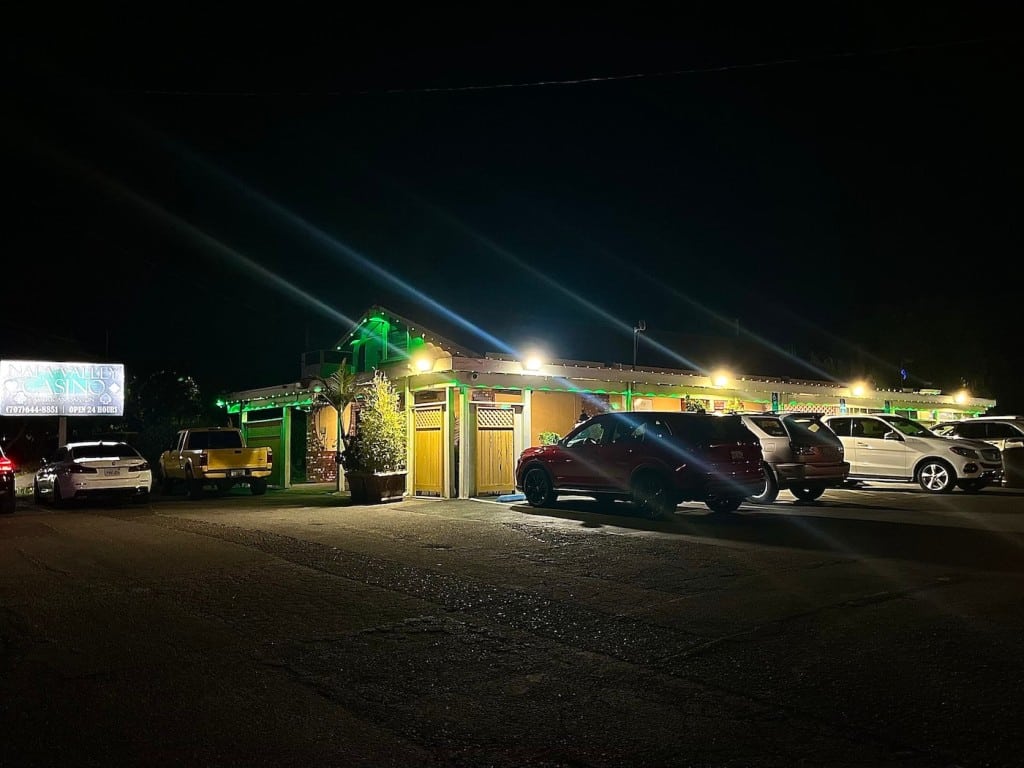 a yellow building lit up in the night surrounded by parked cars