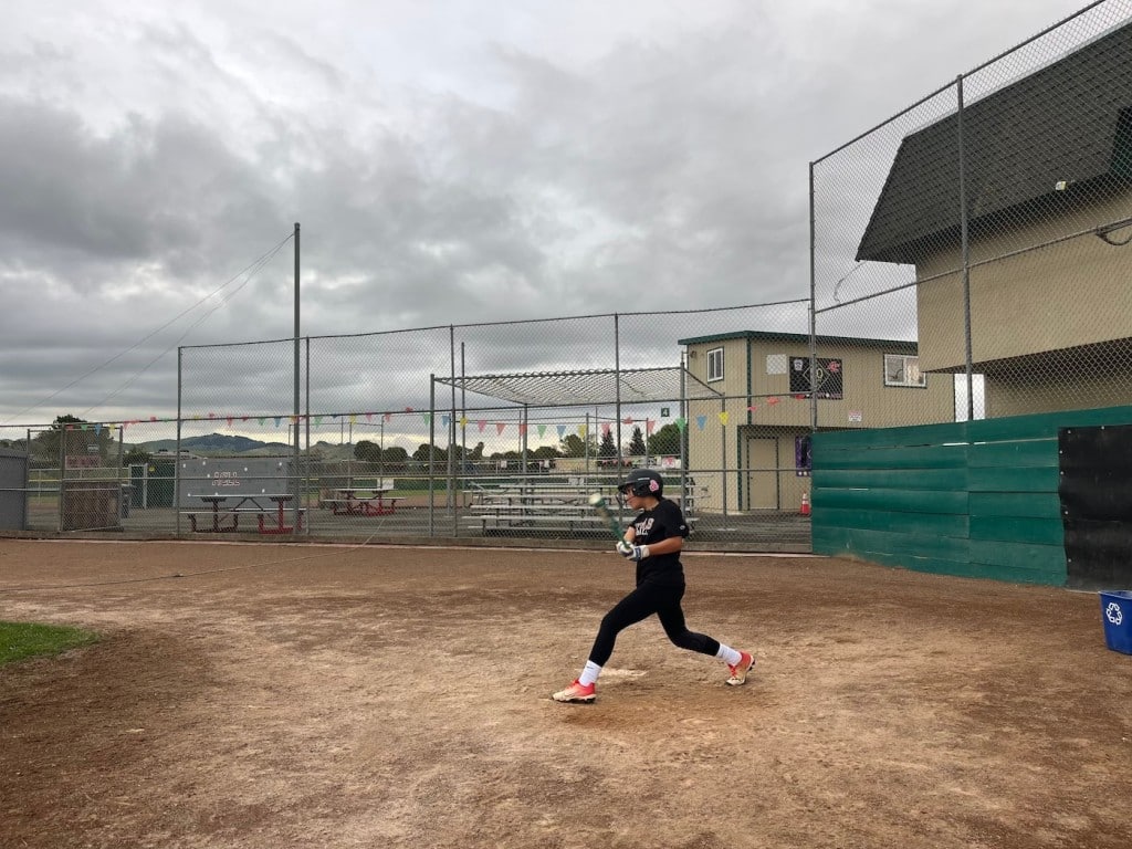 girl batting at baseball