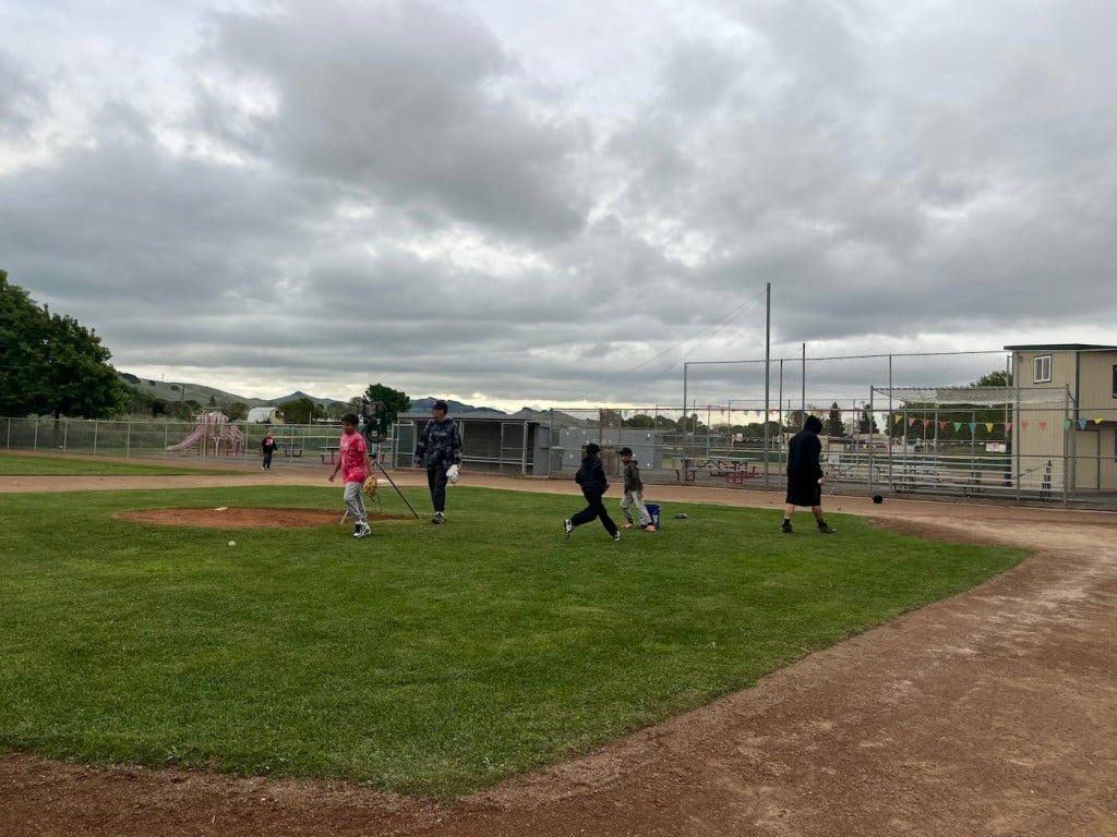 kids playing around on baseball field in foggy day