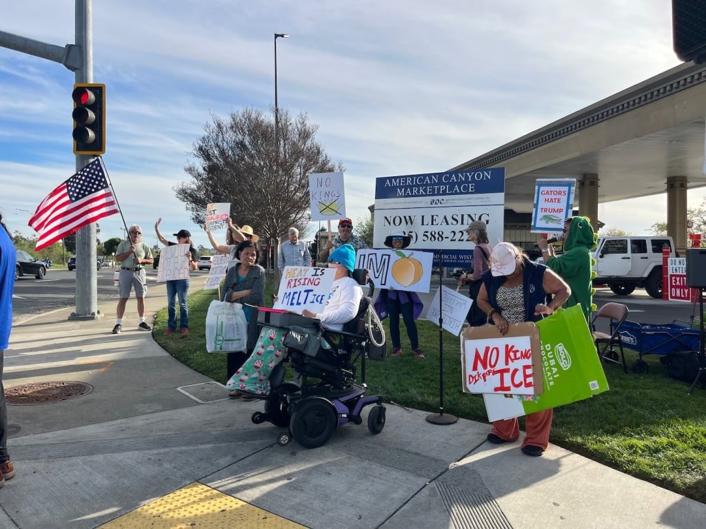 group of people protesting with signs on busy corner
