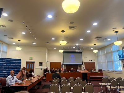 a room filled with empty chairs facing people sitting at tables