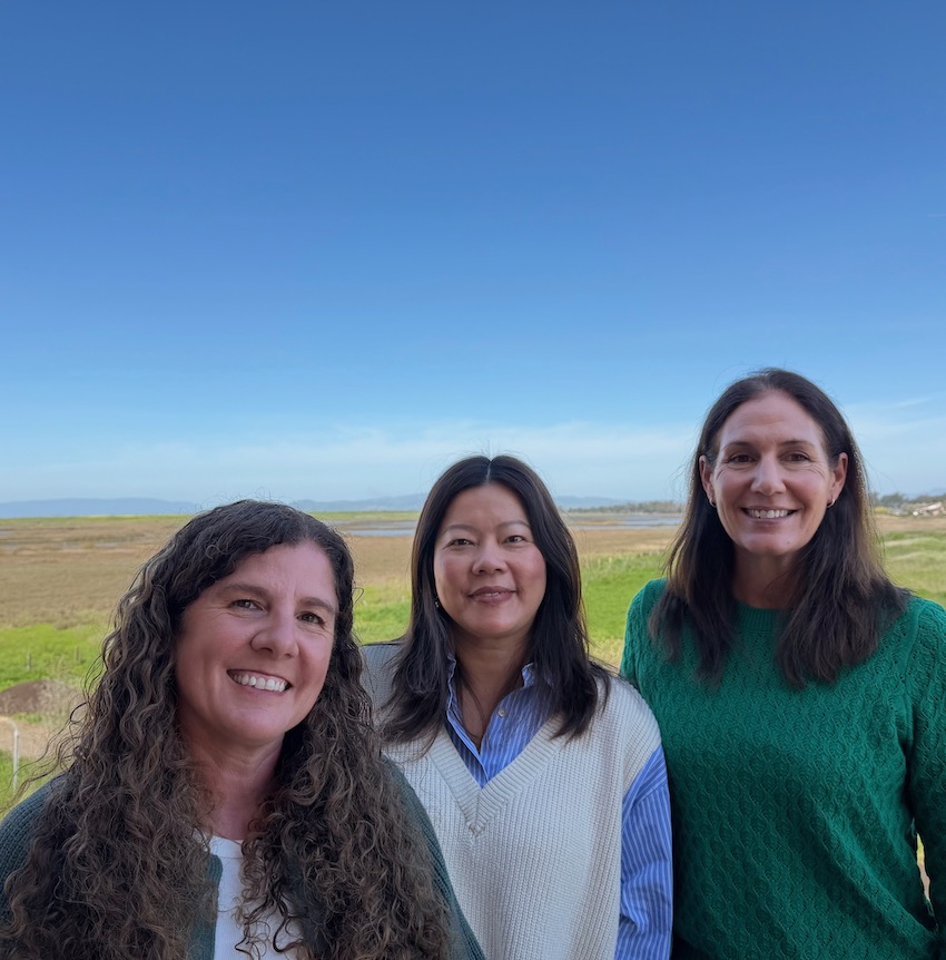 three women standing on a sunny day