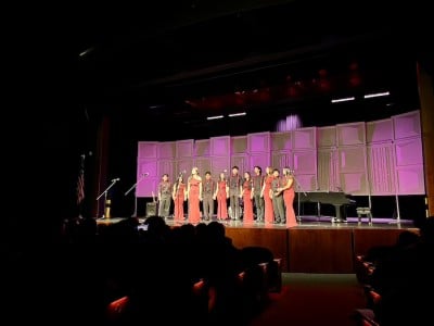 group of kids in gowns and suits singing onstage