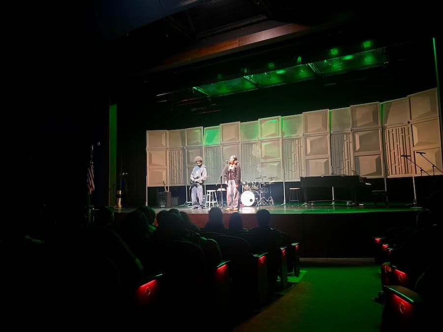 a young woman and young man performing a song onstage