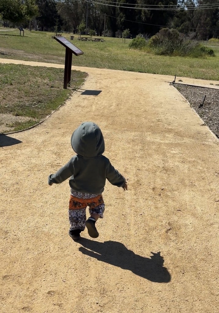 the back of a toddler running down a trail