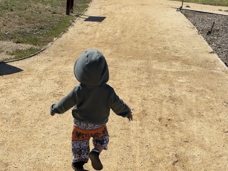 the back of a toddler running down a trail